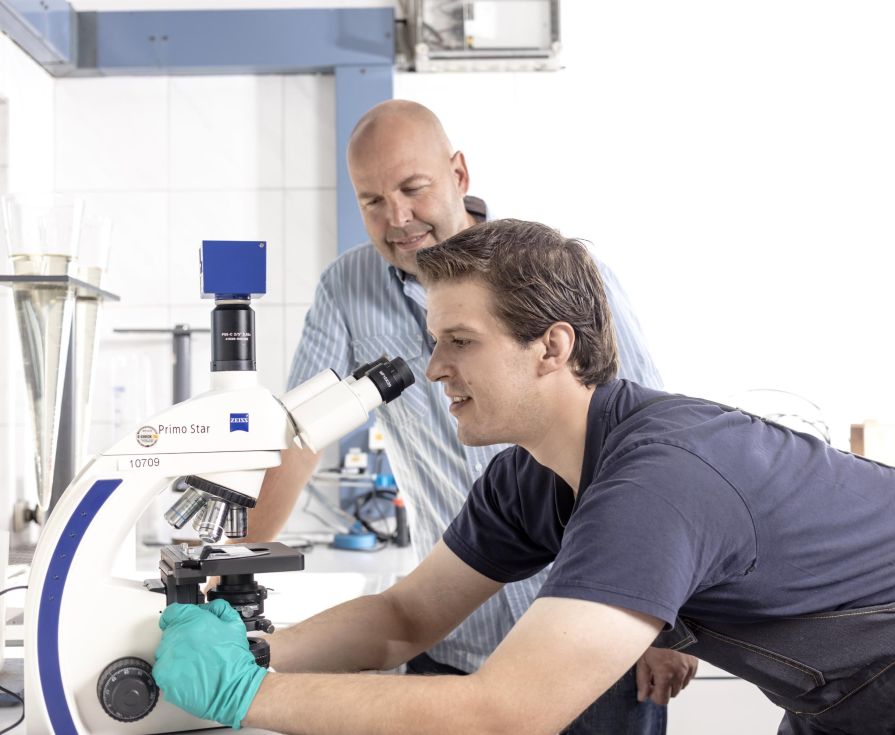 Auszubildender im Labor schaut in ein Mikroskop